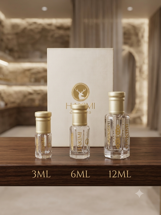 Three clear glass perfume sample bottles with gold caps are displayed on a wooden surface in front of a white box with a gold deer logo and the brand name HAKIMI. The bottles are labeled 3ML, 6ML, and 12ML.