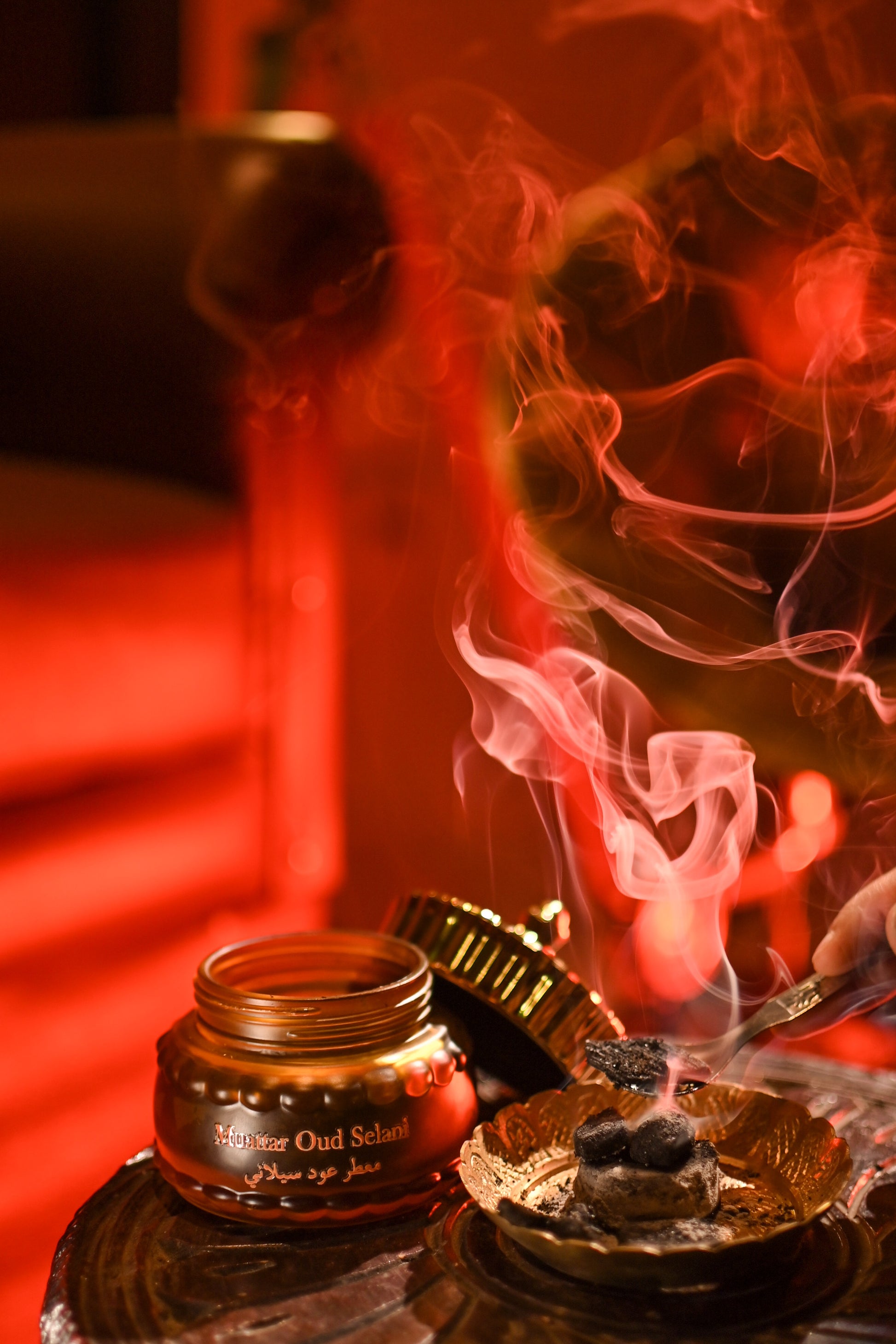 Incense burner with smoke on a reflective surface with a blurred background