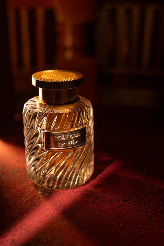 Perfume bottle with gold cap and label on a dark surface