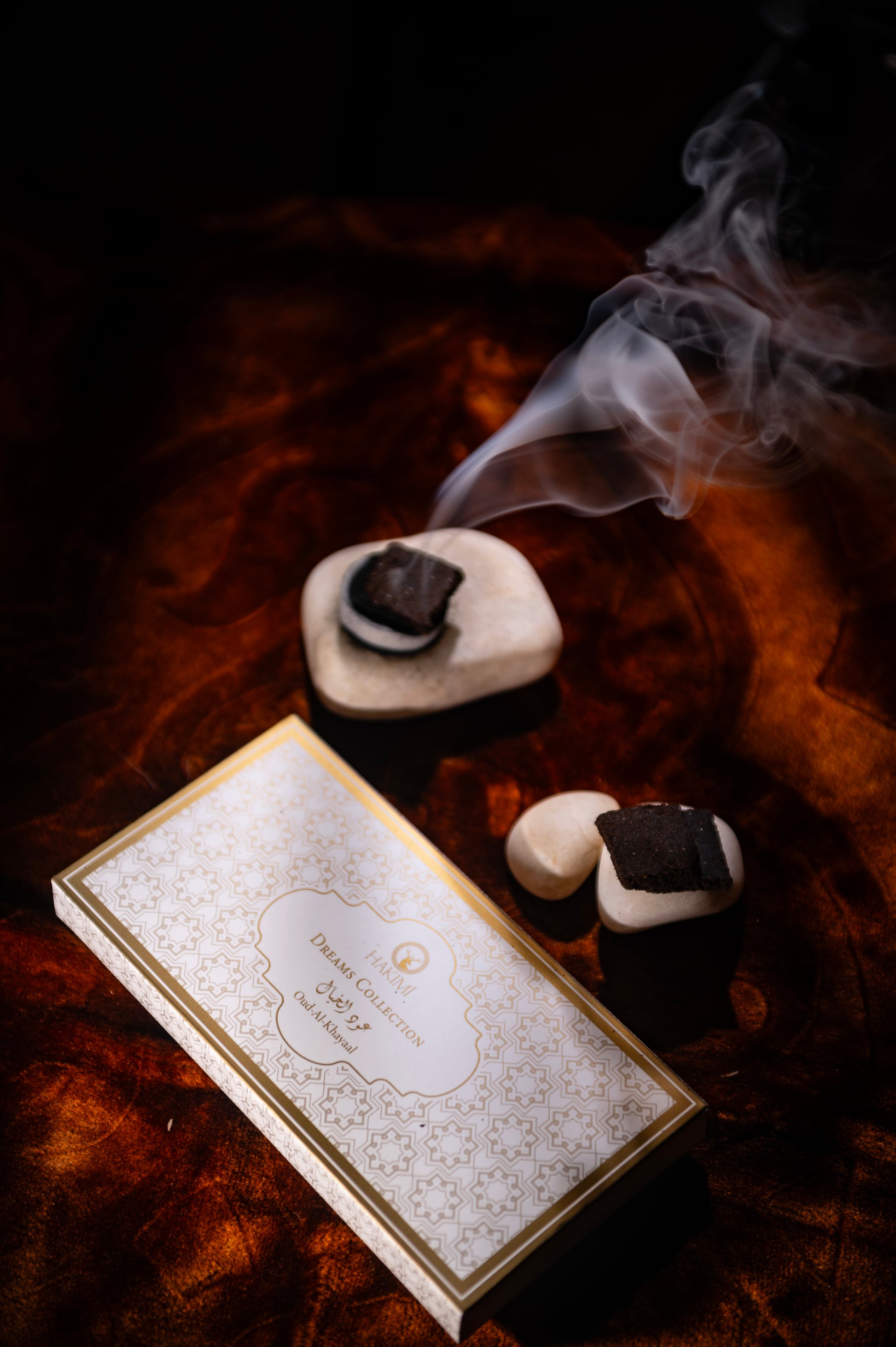 Incense stick with smoke next to a decorative box on a textured surface