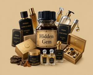 A luxury perfume gift set featuring multiple bottles, boxes, and jars with elegant gold and black packaging, including a central amber glass bottle labeled 'Hidden Gem'. The set is arranged on a solid beige background.